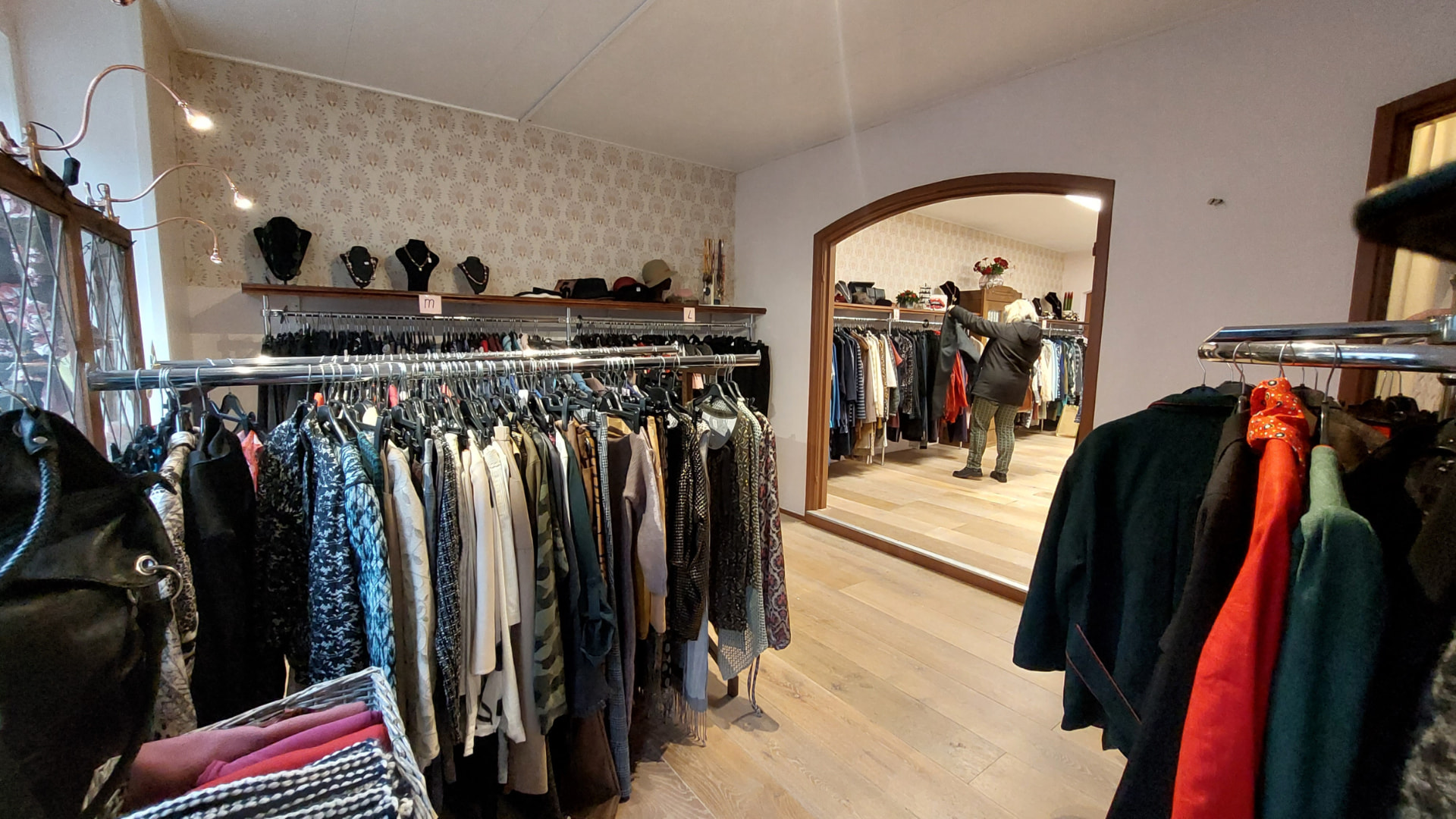 Doorkijk in de winkel met kledingrekken en een grote spiegel